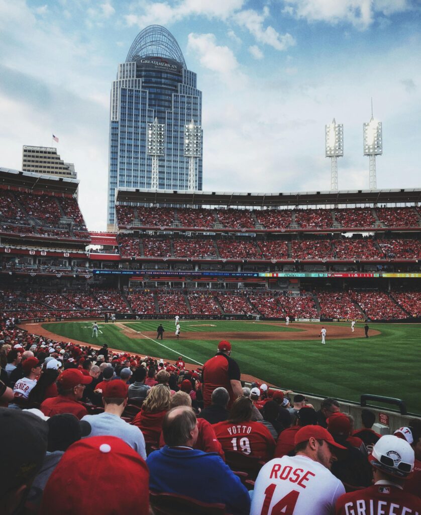 A vibrant scene at a baseball game in Cincinnati with a packed crowd and city skyline backdrop.